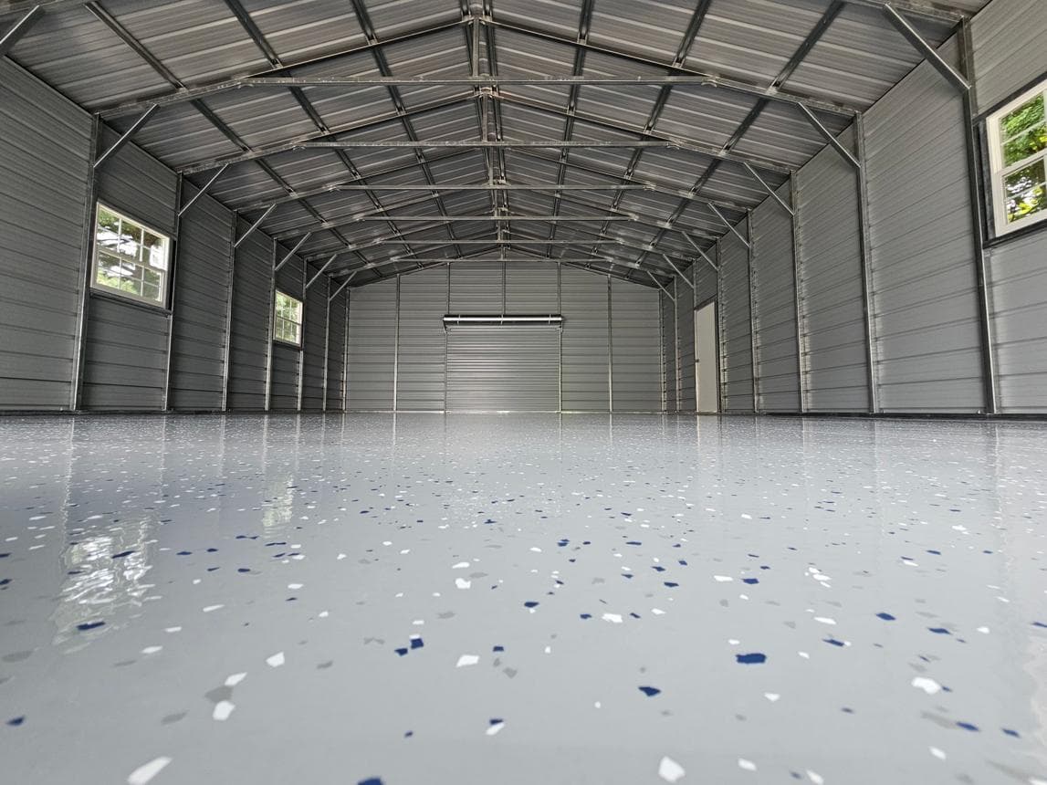 Interior of a metal garage with a glossy epoxy floor containing blue and white flakes.