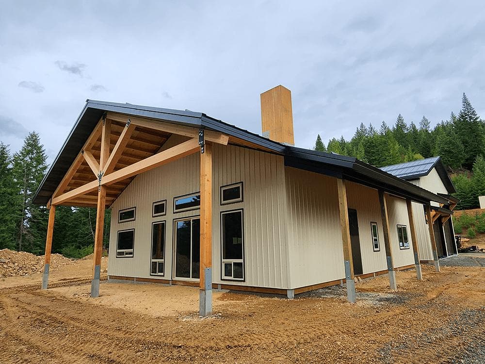 Modern tan house with vertical metal siding, large black-framed windows, and a timber-framed porch.