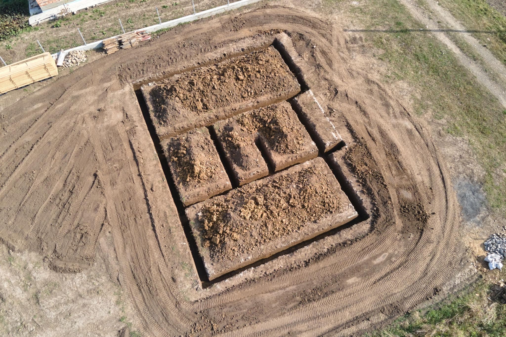 Aerial view of rectangular foundation trenches excavated in a field for a new building.